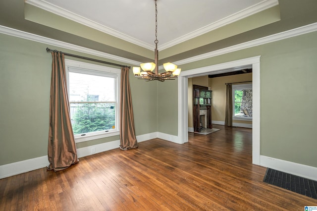 unfurnished dining area featuring crown molding, a healthy amount of sunlight, dark wood-type flooring, and a notable chandelier