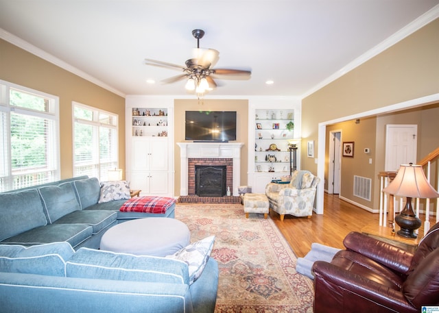 living room featuring ornamental molding, ceiling fan, built in features, a fireplace, and hardwood / wood-style floors