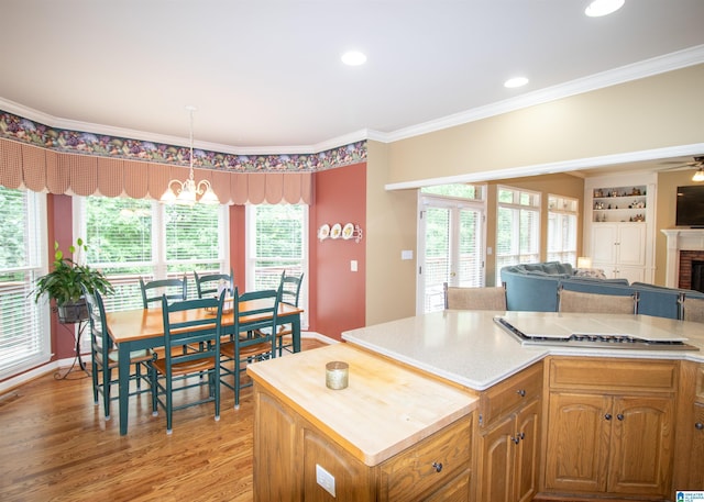 kitchen with a center island, light hardwood / wood-style flooring, decorative light fixtures, a fireplace, and ornamental molding