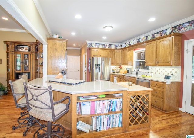 kitchen featuring a breakfast bar, a center island, crown molding, light wood-type flooring, and stainless steel appliances