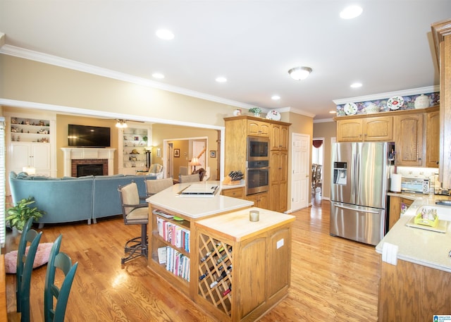 kitchen featuring light hardwood / wood-style flooring, a brick fireplace, built in features, ornamental molding, and appliances with stainless steel finishes