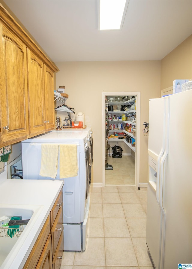 clothes washing area featuring cabinets, light tile patterned floors, sink, and washing machine and clothes dryer