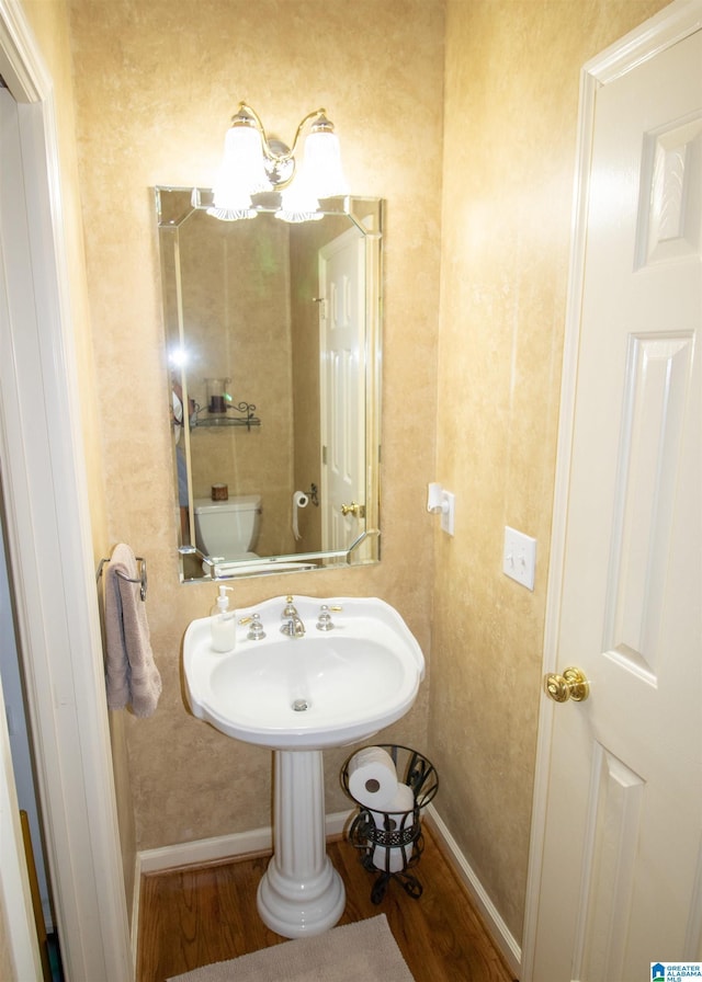 bathroom with hardwood / wood-style flooring, toilet, and sink