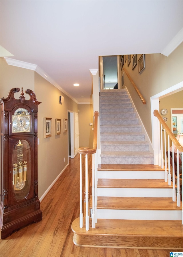 stairs featuring hardwood / wood-style floors and ornamental molding