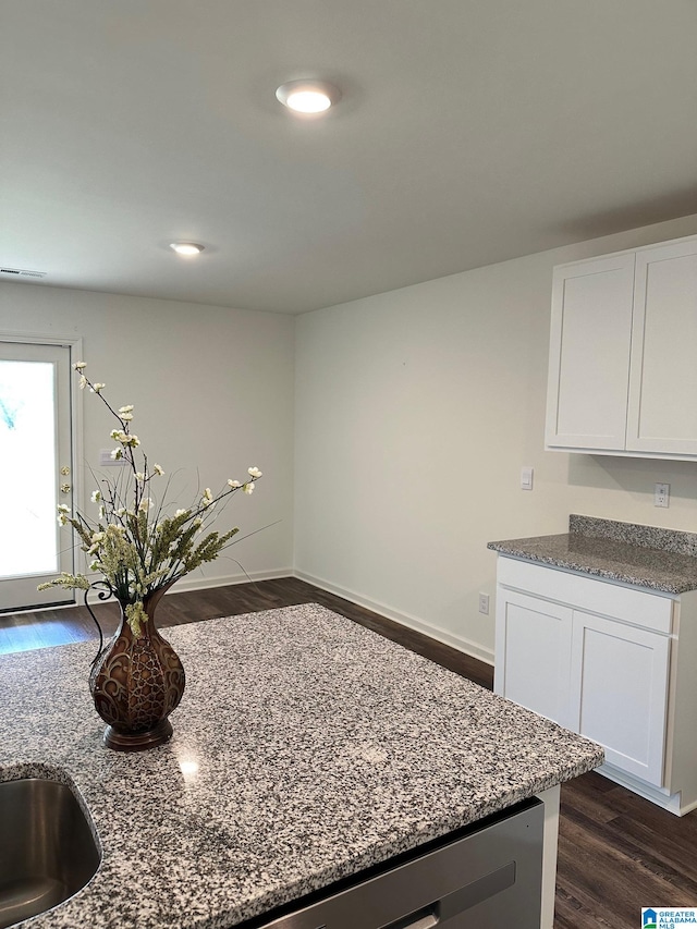 kitchen with sink, dark hardwood / wood-style flooring, white cabinetry, and dark stone countertops