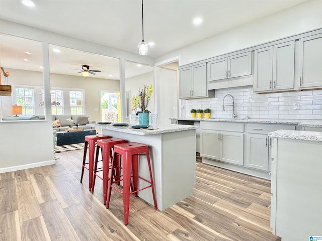 kitchen with gray cabinetry, sink, a kitchen island, and decorative light fixtures