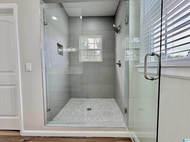 bathroom featuring a shower with door, plenty of natural light, and hardwood / wood-style flooring