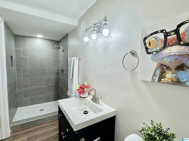 bathroom featuring tiled shower, vanity, hardwood / wood-style flooring, and toilet