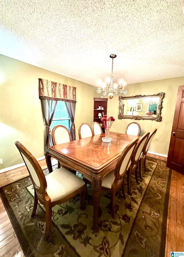 dining space with an inviting chandelier, a textured ceiling, and hardwood / wood-style floors