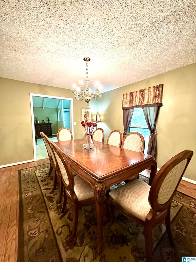 dining area featuring wood-type flooring, a notable chandelier, and a textured ceiling