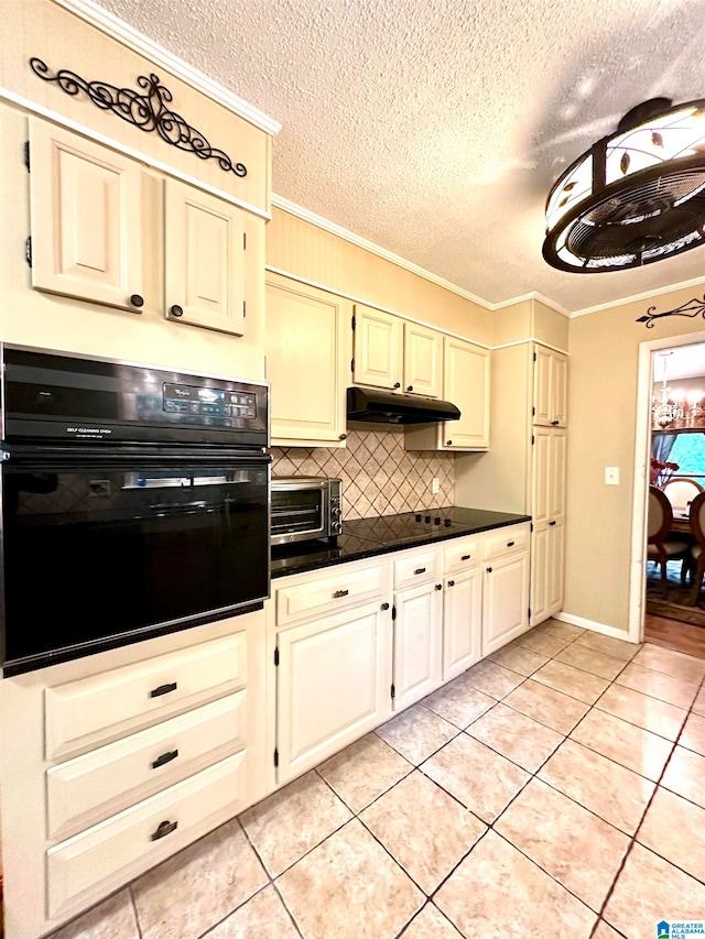 kitchen with light tile patterned flooring, crown molding, tasteful backsplash, black oven, and a textured ceiling