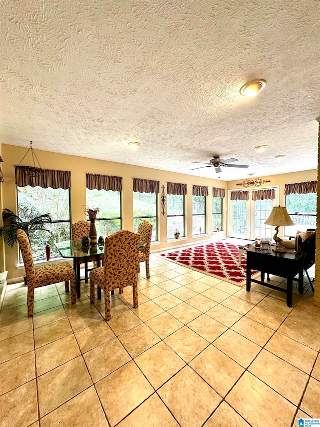 tiled dining space with a textured ceiling, a wealth of natural light, and ceiling fan