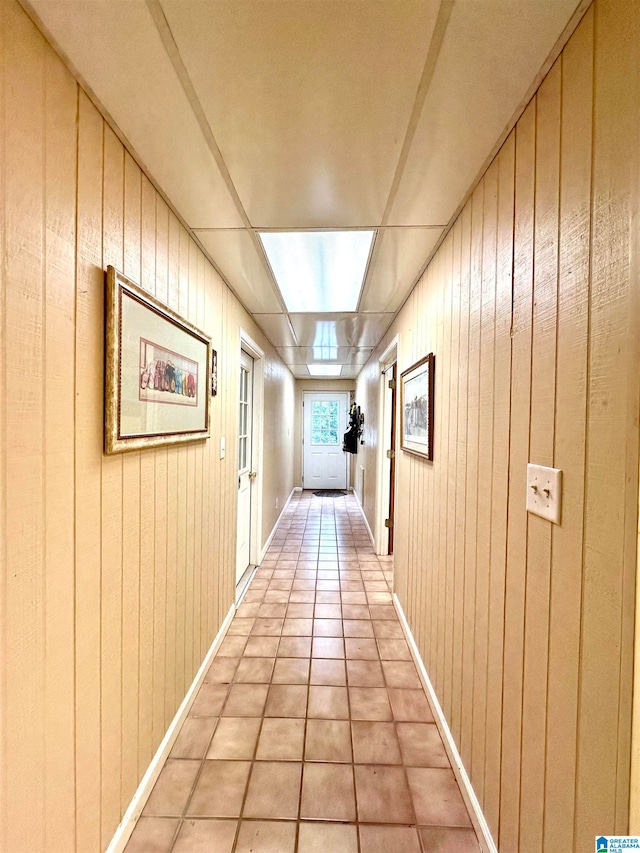 corridor with wood walls and tile patterned floors