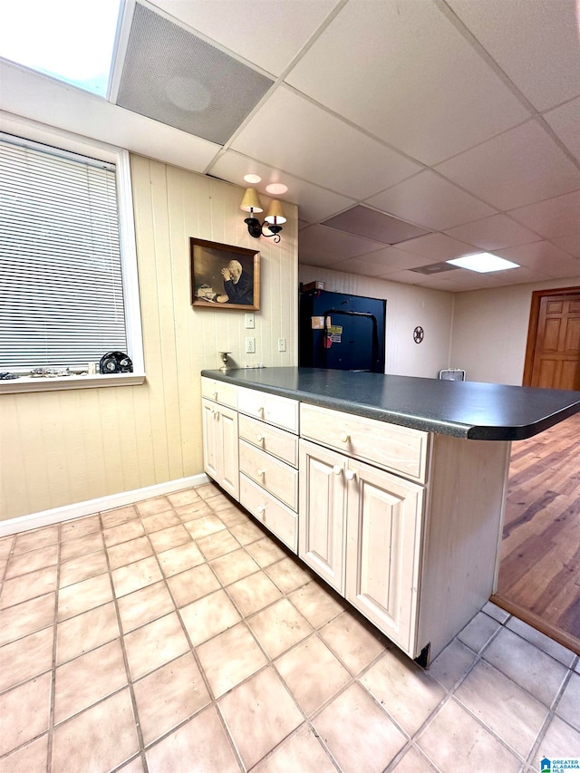 kitchen featuring light tile patterned flooring, kitchen peninsula, and a drop ceiling