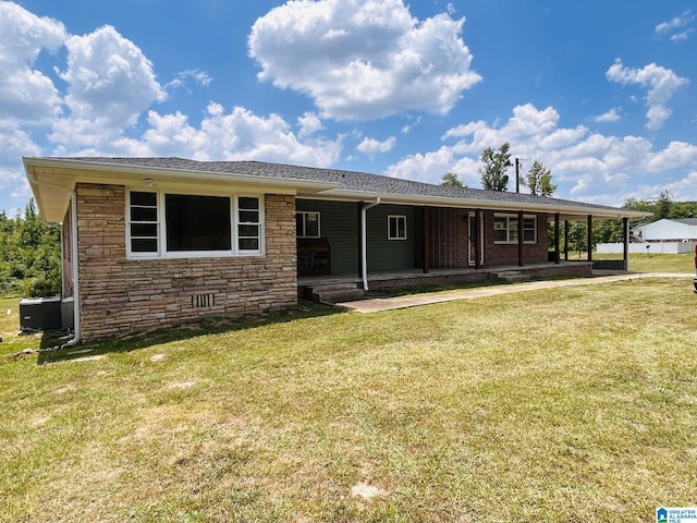 back of property with a porch, central air condition unit, a lawn, and stone siding