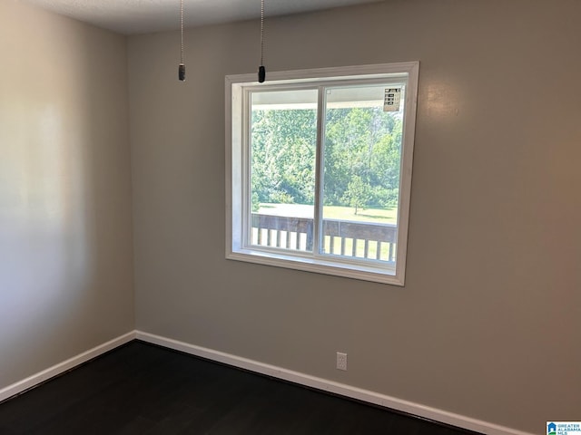 spare room featuring baseboards and dark wood-style flooring