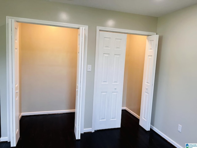 unfurnished bedroom with a closet, baseboards, and dark wood-style floors