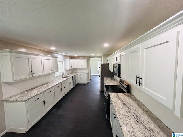 kitchen with sink, white cabinetry, dark hardwood / wood-style floors, stainless steel appliances, and light stone countertops