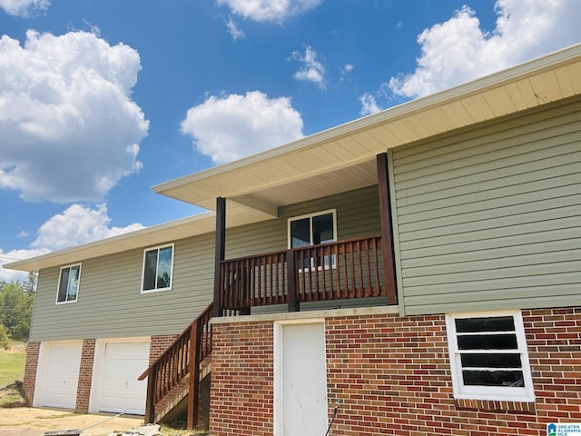 rear view of property featuring brick siding, stairway, a porch, driveway, and an attached garage