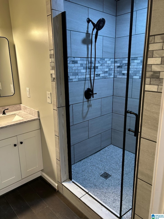 full bath featuring baseboards, vanity, and a shower stall