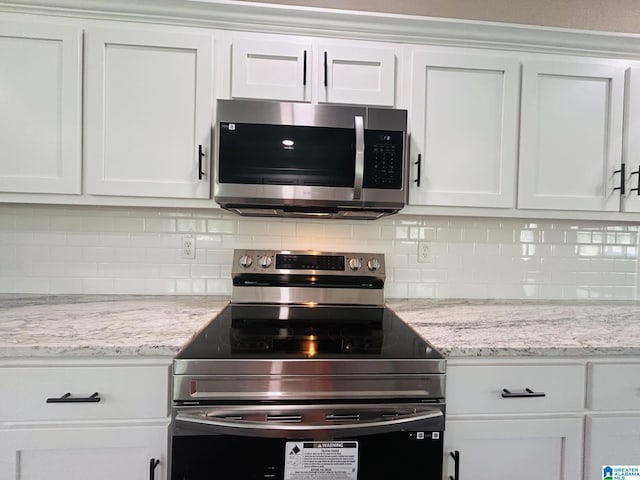 kitchen featuring decorative backsplash, light stone countertops, appliances with stainless steel finishes, and white cabinetry