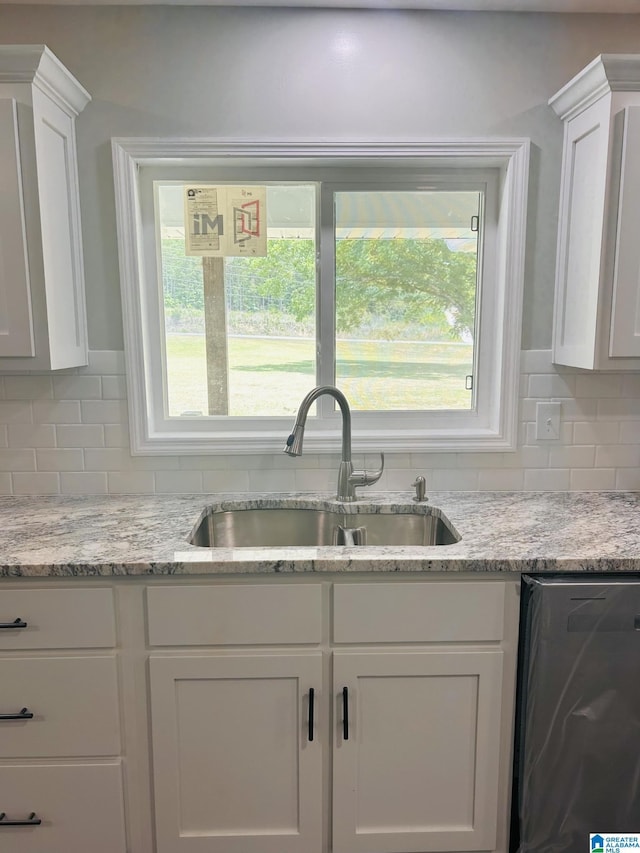 kitchen with a sink, tasteful backsplash, dishwasher, and white cabinetry