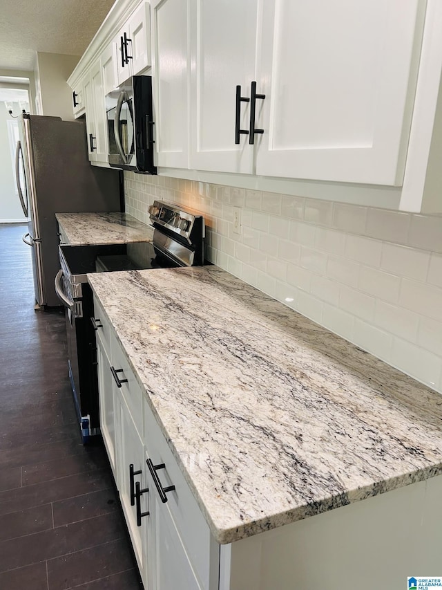 kitchen featuring white cabinets, dark wood-style floors, light stone countertops, and stainless steel appliances