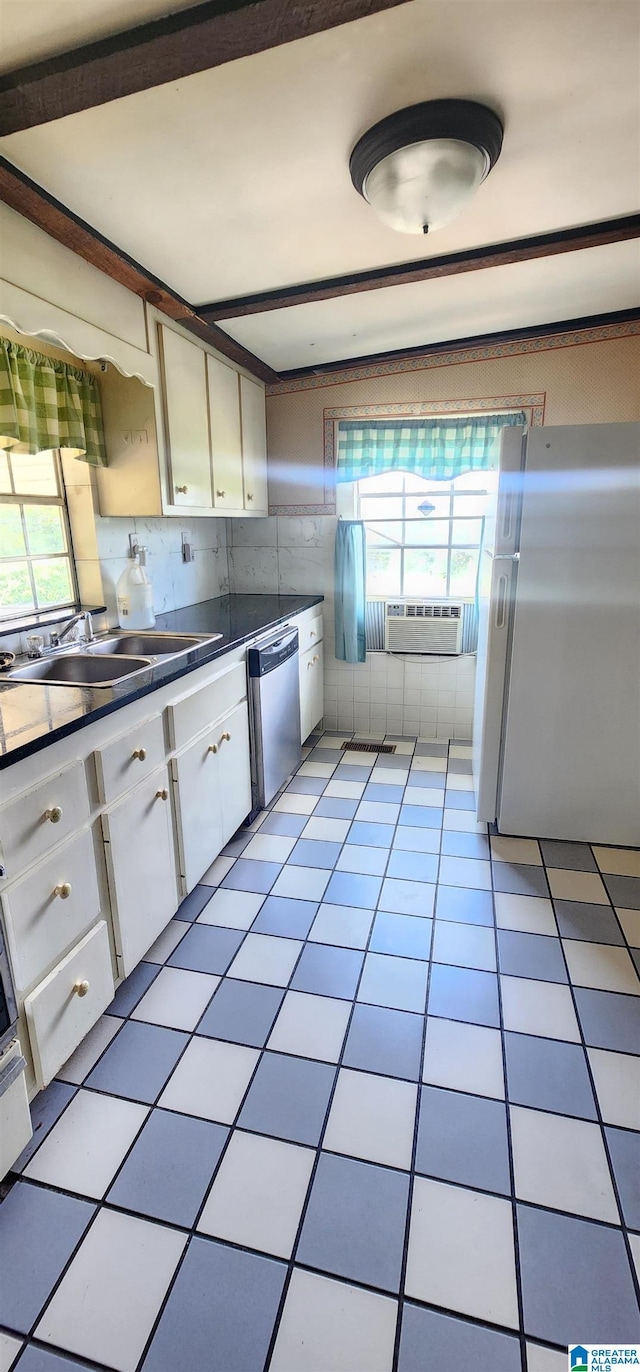 kitchen with light tile patterned flooring, sink, stainless steel dishwasher, white fridge, and white cabinets