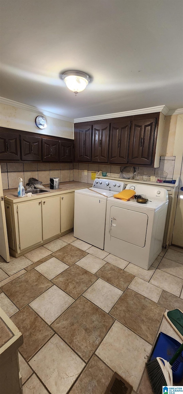 laundry room featuring cabinets, crown molding, and washer and clothes dryer