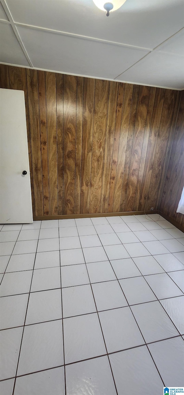 unfurnished room with light tile patterned floors and wooden walls