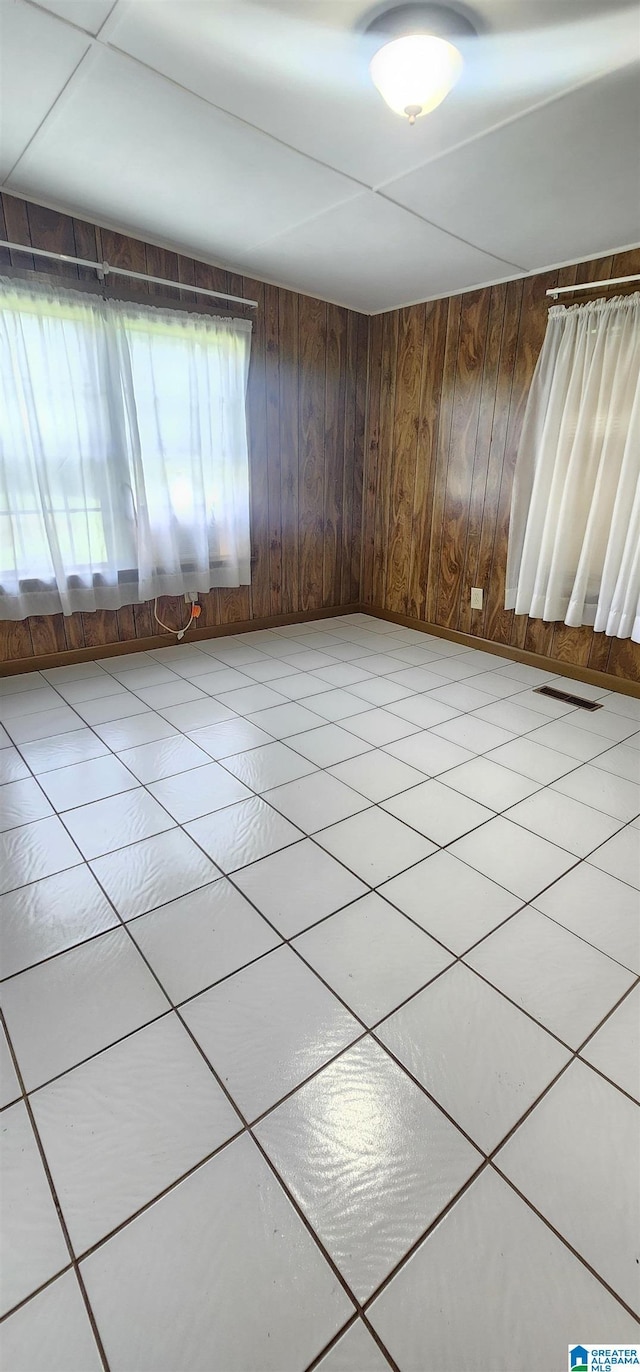 tiled empty room featuring wood walls