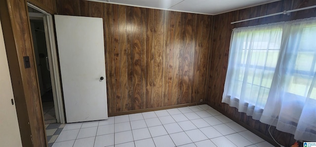 tiled spare room featuring wooden walls