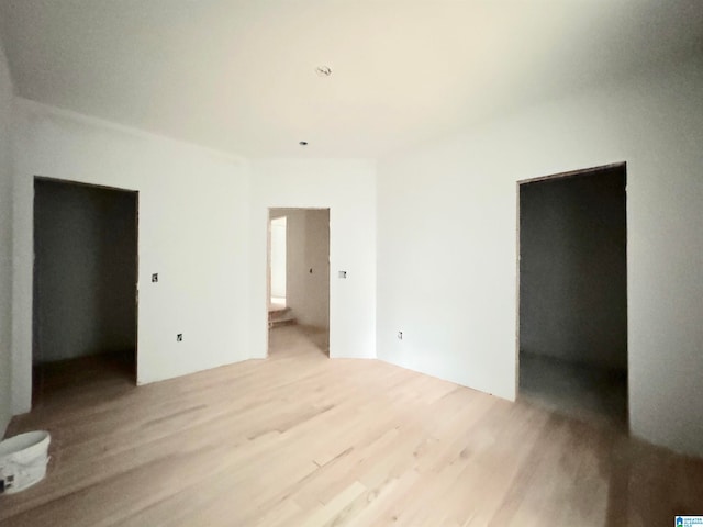 unfurnished bedroom featuring light wood-type flooring, a spacious closet, a closet, and connected bathroom