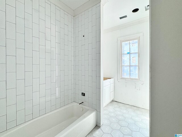 bathroom featuring tile patterned floors, tiled shower / bath, and vanity