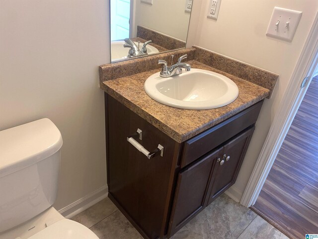 bathroom with tile patterned flooring, vanity, toilet, and baseboards