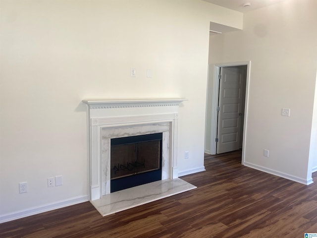 unfurnished living room featuring dark wood finished floors, baseboards, and a premium fireplace