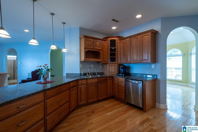 kitchen featuring sink, dark stone countertops, hanging light fixtures, stainless steel dishwasher, and light hardwood / wood-style flooring