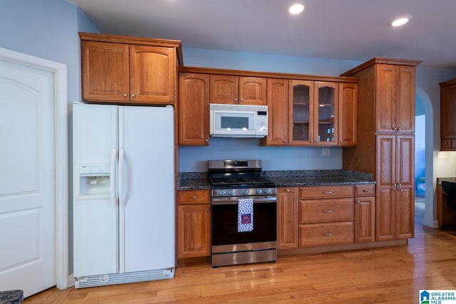 kitchen featuring light wood-type flooring, white appliances, and dark stone counters