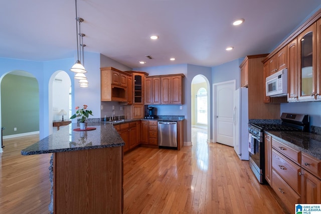 kitchen featuring sink, appliances with stainless steel finishes, decorative light fixtures, kitchen peninsula, and dark stone counters