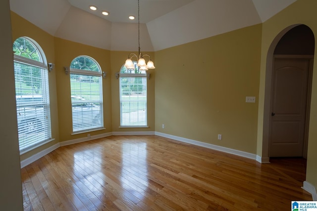 unfurnished room featuring lofted ceiling, a notable chandelier, and light wood-type flooring