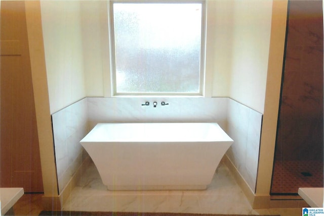 bathroom with a washtub and tile walls