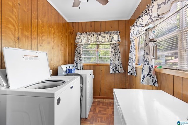 laundry room with ceiling fan, wooden walls, dark parquet flooring, ornamental molding, and washing machine and clothes dryer