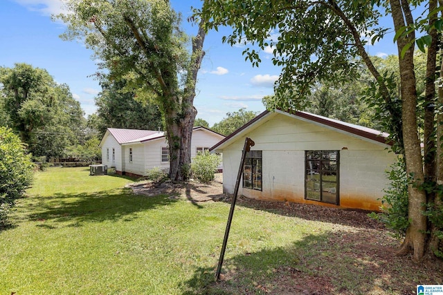 back of property featuring central AC and a yard