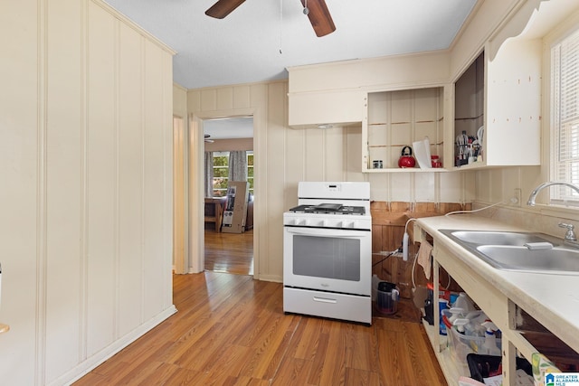 kitchen featuring ceiling fan, white gas range, sink, and light wood-type flooring