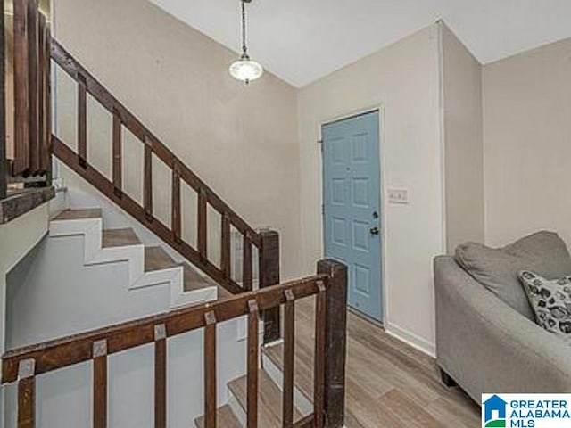 foyer featuring stairway, light wood-style flooring, baseboards, and vaulted ceiling