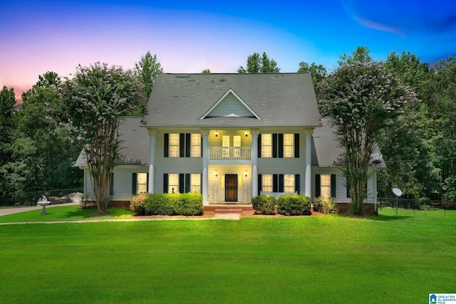 view of front of home with a lawn and a balcony