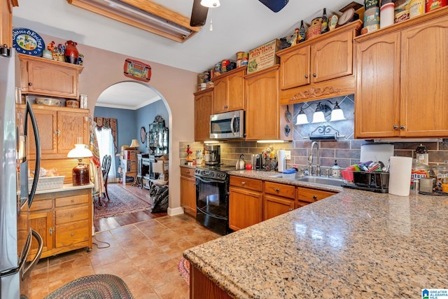 kitchen featuring sink, ceiling fan, stainless steel appliances, light stone counters, and decorative backsplash