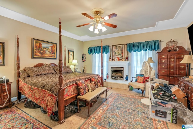 carpeted bedroom with ceiling fan and a tile fireplace