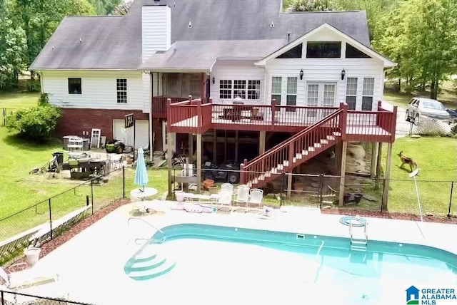 rear view of property featuring a swimming pool side deck, a patio area, and a lawn