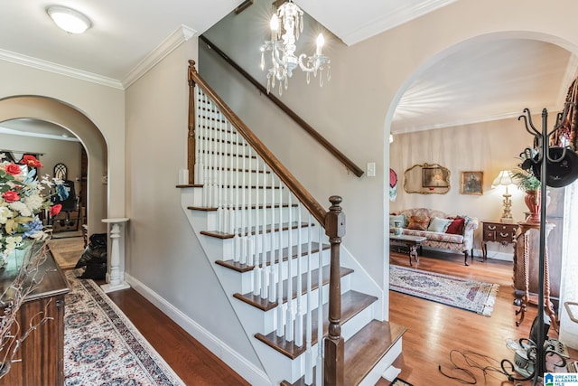 stairway featuring hardwood / wood-style flooring, crown molding, and an inviting chandelier